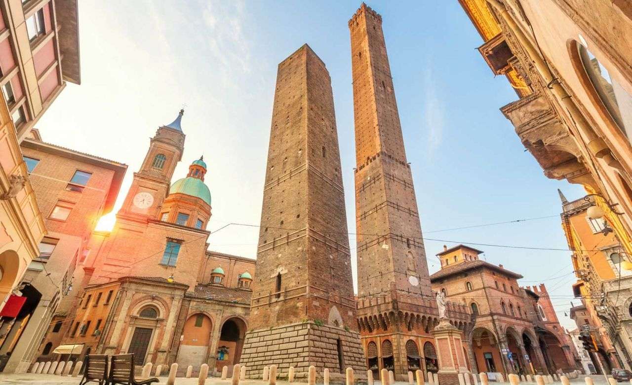 Bolonga Towers with the core of the Italian city in the background. The sky is blue and sunny.